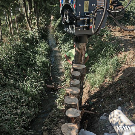 Enfonce-pieux hydraulique enfonçant un poteau près d’un ruisseau.